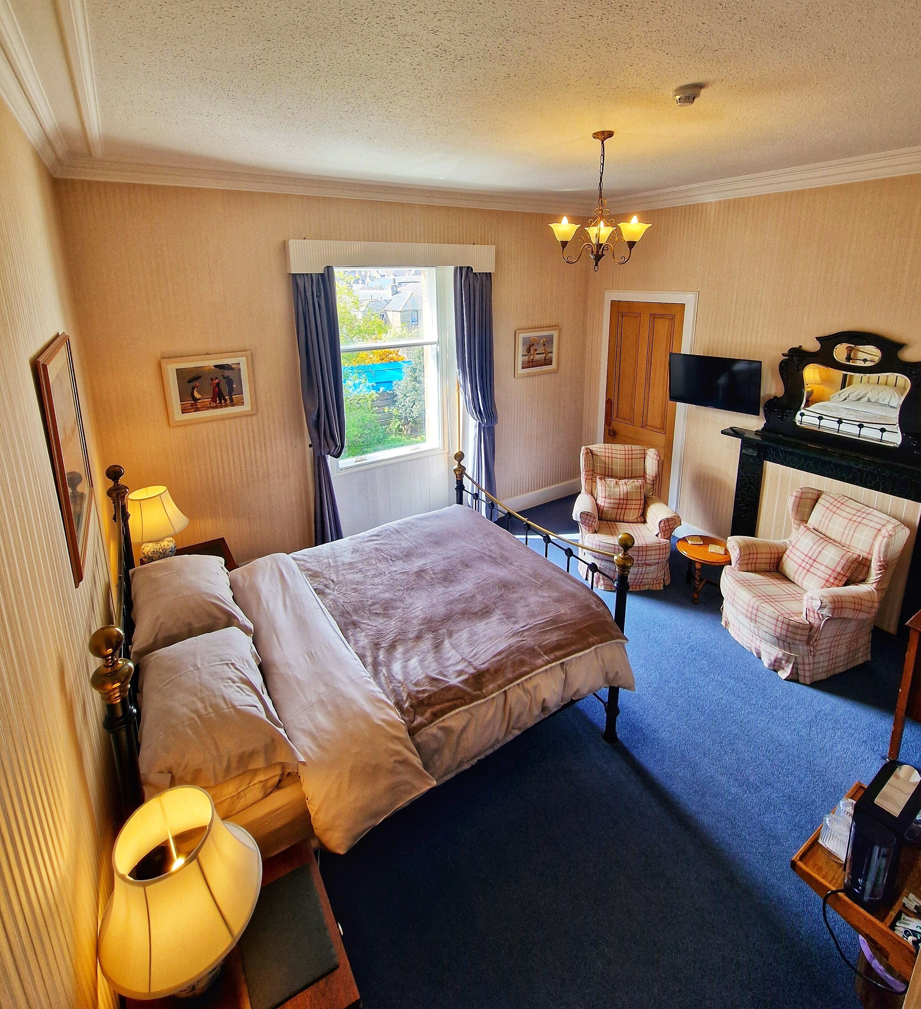 Une chambre avec un grand lit, une chaise, une télévision et une cheminée.