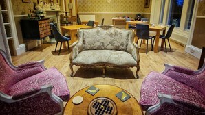 A room with a sofa, two armchairs, a dining table, and a chandelier. - The Pines Guesthouse (Elgin)