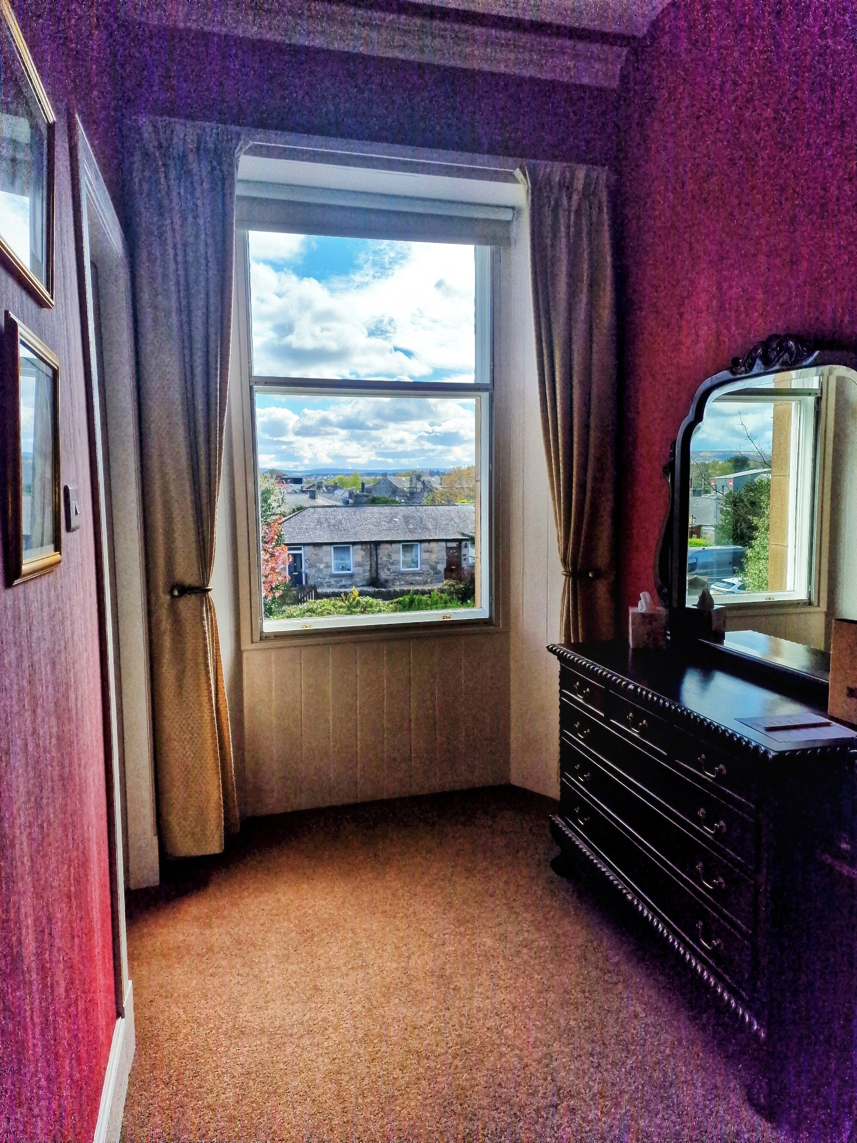 Een kamer met een groot raam, een dressoir en een spiegel.