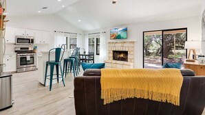 A modern kitchen with white cabinets, stainless steel appliances, and teal bar stools. - Woodacre Cottage I   Minutes to Jacob's Well (Wimberley)