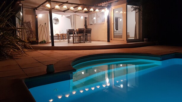 Ein Poolbereich mit überdachter Terrasse, einem Esstisch und Stühlen.