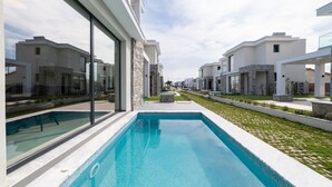 Un immeuble résidentiel moderne doté d’une piscine, de détails en pierre et de grandes fenêtres.