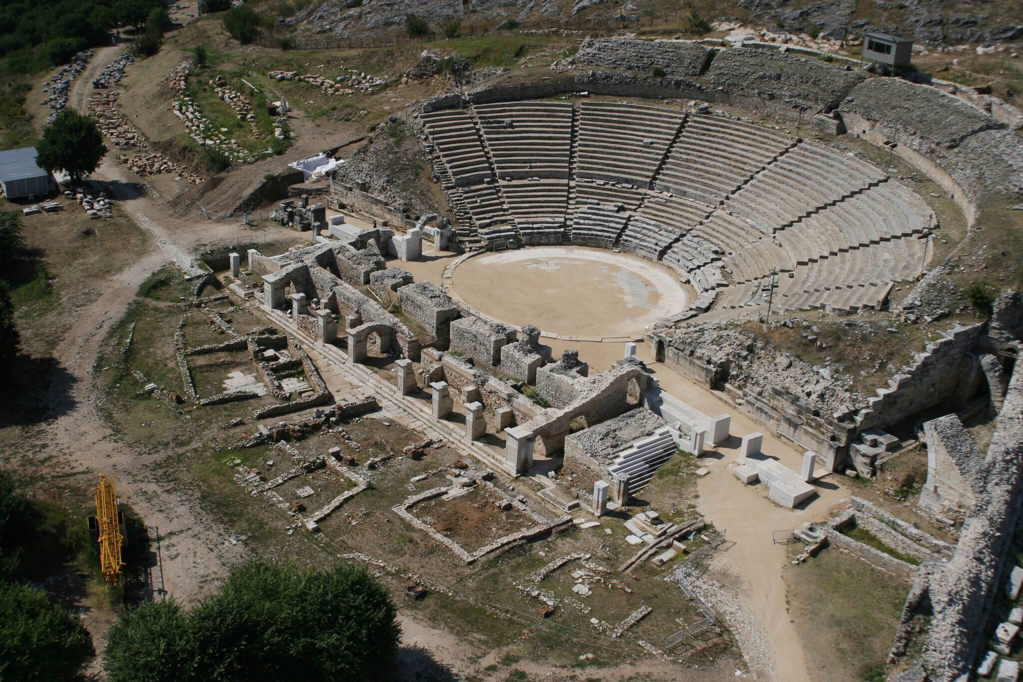 An ancient amphitheater with a central stage and tiered seating.