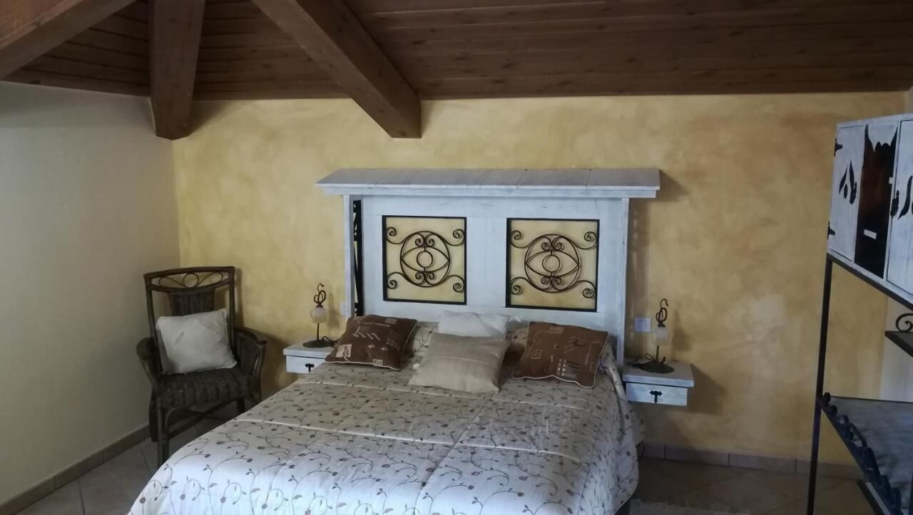 A bedroom with a bed, two nightstands, a chair, and a shelf with decorative items.