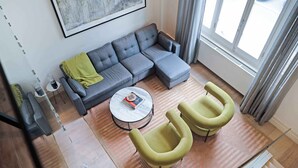 Una sala moderna con un sofá seccional gris, una mesa de centro redonda y dos sillones amarillos.