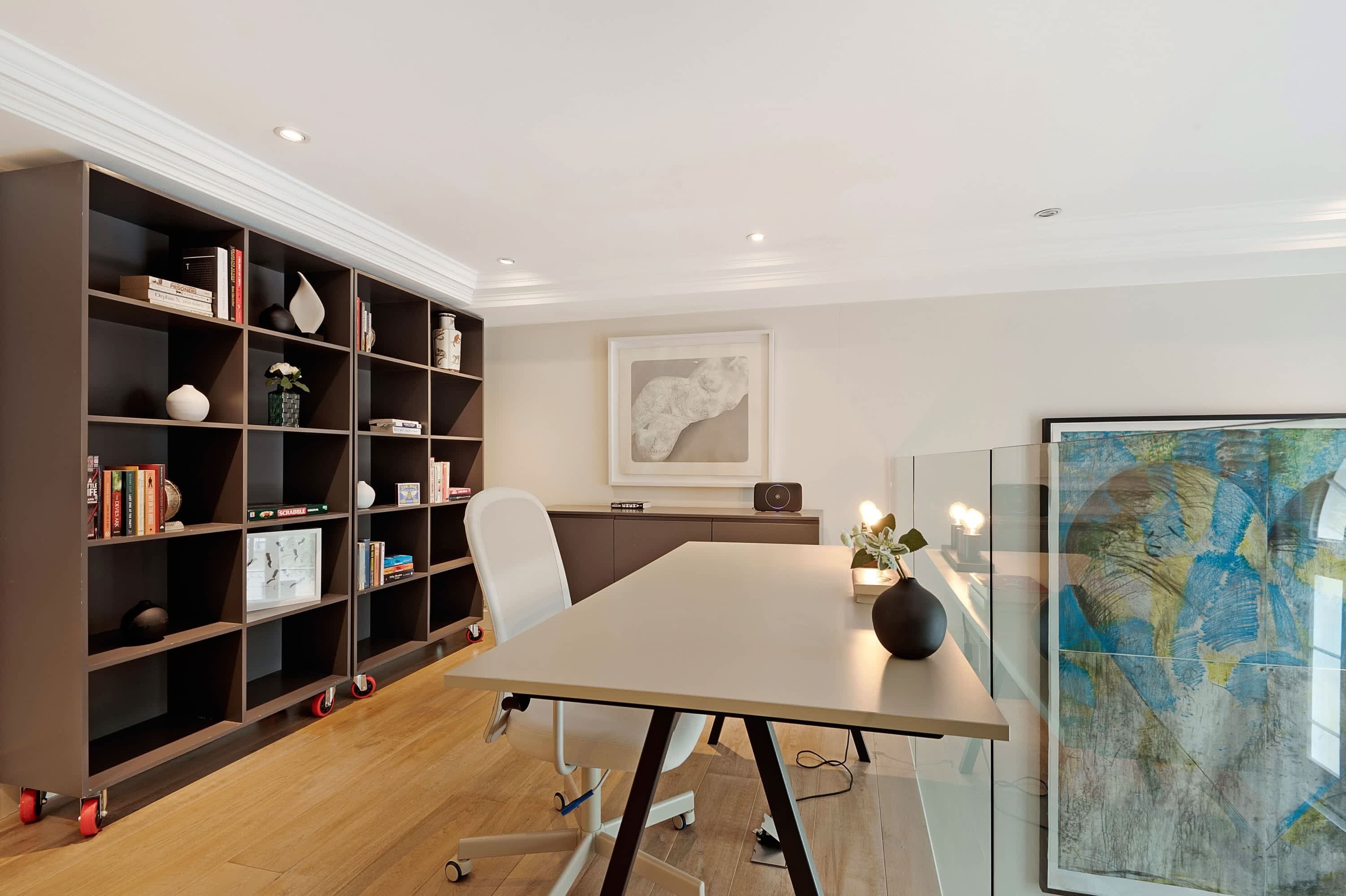 Una sala conferenze moderna con un grande tavolo, una libreria e un'ampia pittura astratta.