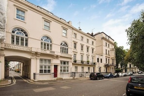 A multi-story building with a classic architectural style, featuring a prominent entrance with a red door and a balcony. - The Artists Hideaway-2 bed Paddington, by Out of Office Lifestyle (Greater London)