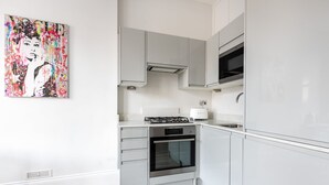 Moderni keittiö, jossa on valkoiset kaapit, sisäänrakennettu uuni ja leivänpaahdin.