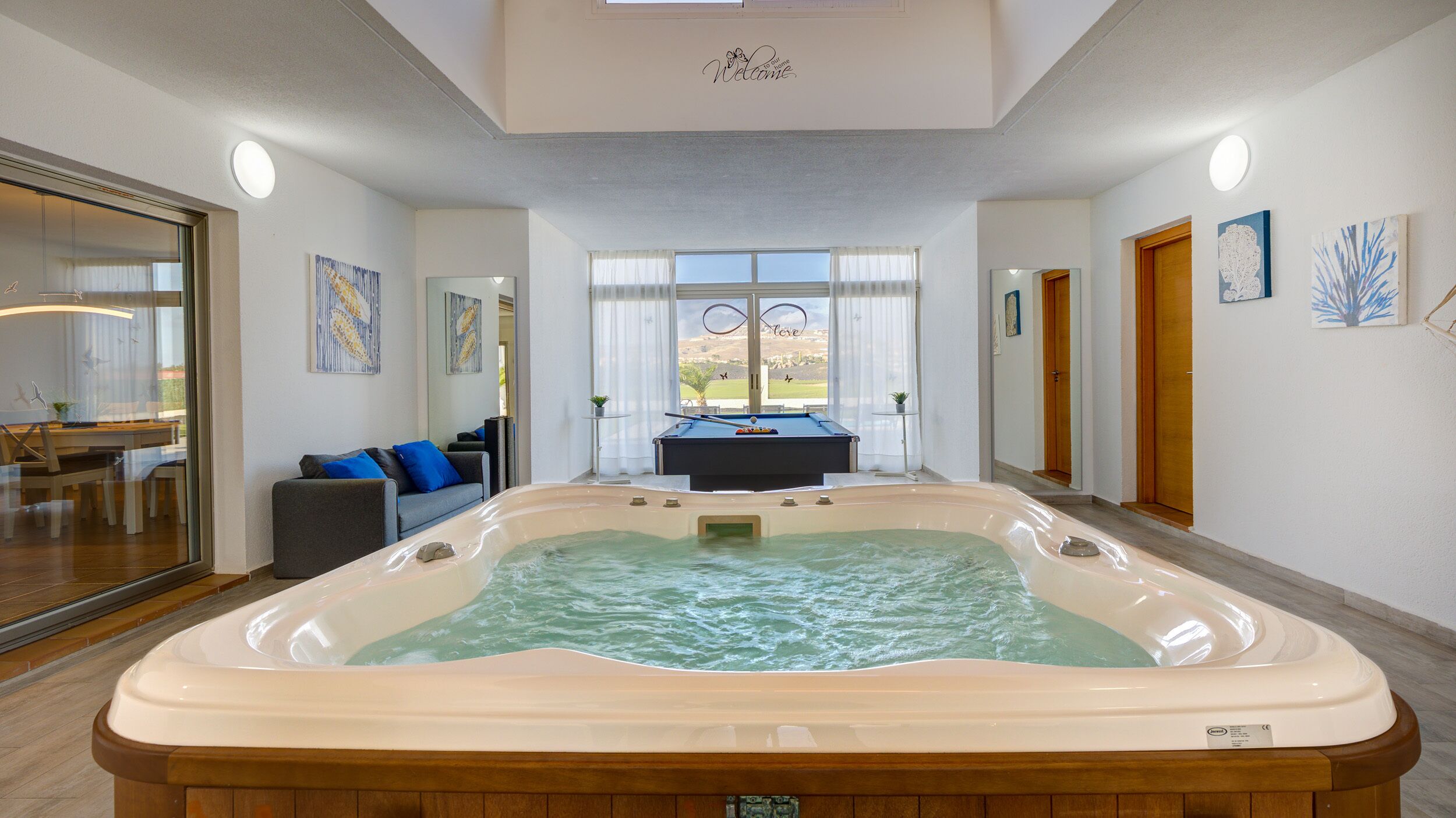 A room with a hot tub, a pool table, and a view of a golf course.
