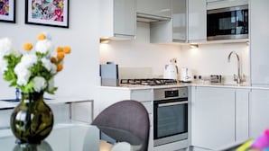 Una cucina moderna con mobili bianchi, un piano cottura a gas, un forno, un microonde e un lavandino.
