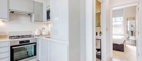 A modern kitchen with white cabinetry, a built-in oven, and a gas stove.