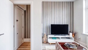 Ein modernes Wohnzimmer mit Fernseher, einer Dekovase und einer Sitzecke.