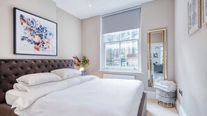Una camera da letto con un letto grande, una finestra vista, uno specchio e un'opera d'arte appesa al muro.