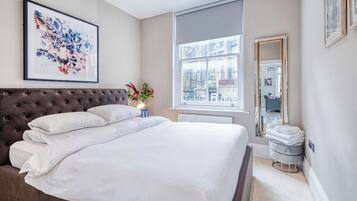 Un dormitorio con una cama grande, una ventana con vistas, un espejo y una obra de arte enmarcada en la pared.