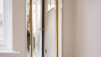 Un baño con un espejo grande, una pila de toallas blancas y una ventana.