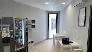 Une chambre propre et moderne, équipée d’un distributeur automatique, d’un four à micro-ondes et d’une table avec des chaises.