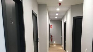 Un couloir doté d’un plancher en bois, de portes noires et d’un éclairage encastré.