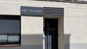 Une entrée d’immeuble avec une enseigne indiquant « HEY ROOMS » et un numéro de téléphone.