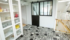 A room with a patterned floor, a white cabinet with glass doors, a black door, and a window with curtains. - Les Tournesols **, 2-bedroom 2-bathroom apartment in the historic heart of Kaysersberg (Kaysersberg-Vignoble)