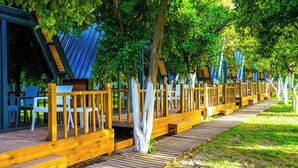 A covered outdoor seating area with wooden railings, tables, and chairs. - Castle Park Hotel (Kemer)
