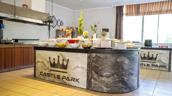 Un área de cocina con encimera de mármol identificada con 'CASTLE PARK', varios cuencos y una ventana con cortinas.