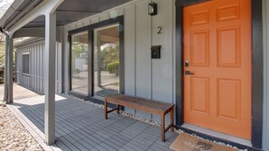 Un porche abrité avec un banc, une porte orange et une boîte aux lettres.