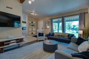 Un salon moderne avec un téléviseur à écran plat, un canapé, un fauteuil et une table basse.