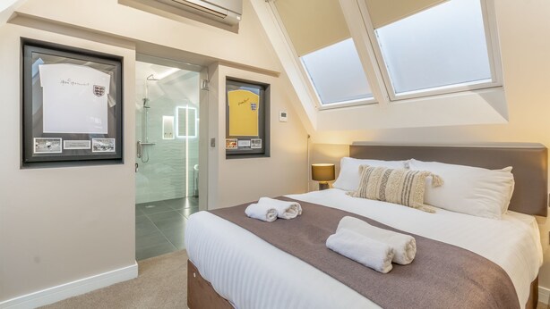 A hotel room with a bed, a window, a framed certificate, and a bathroom visible through an open door. - The Old School House & Rooms- The Lace Market  (Nottingham)