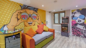 A room with a colorful mural, a sofa with cushions, and a small table with a toy. - The Old School House & Rooms- The Lace Market  (Nottingham)