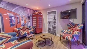 A room with a red telephone booth, a sofa set, a round table, and a wall-mounted TV. - The Old School House & Rooms- The Lace Market  (Nottingham)
