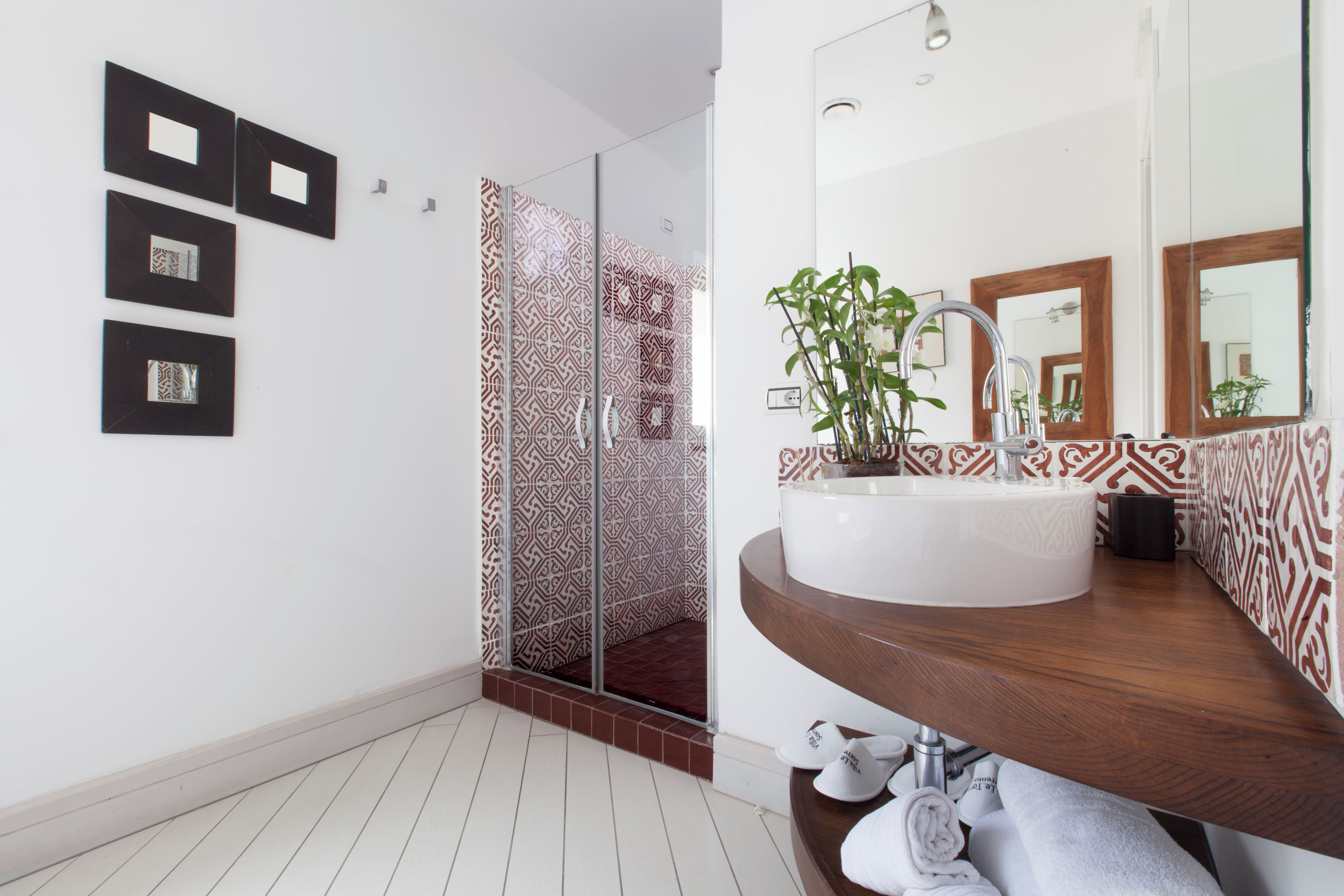 Une salle de bain moderne avec un grand miroir, un lavabo blanc et des carreaux à motifs.