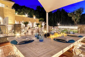 An outdoor dining area with a marble table, white chairs, and blue placemats.