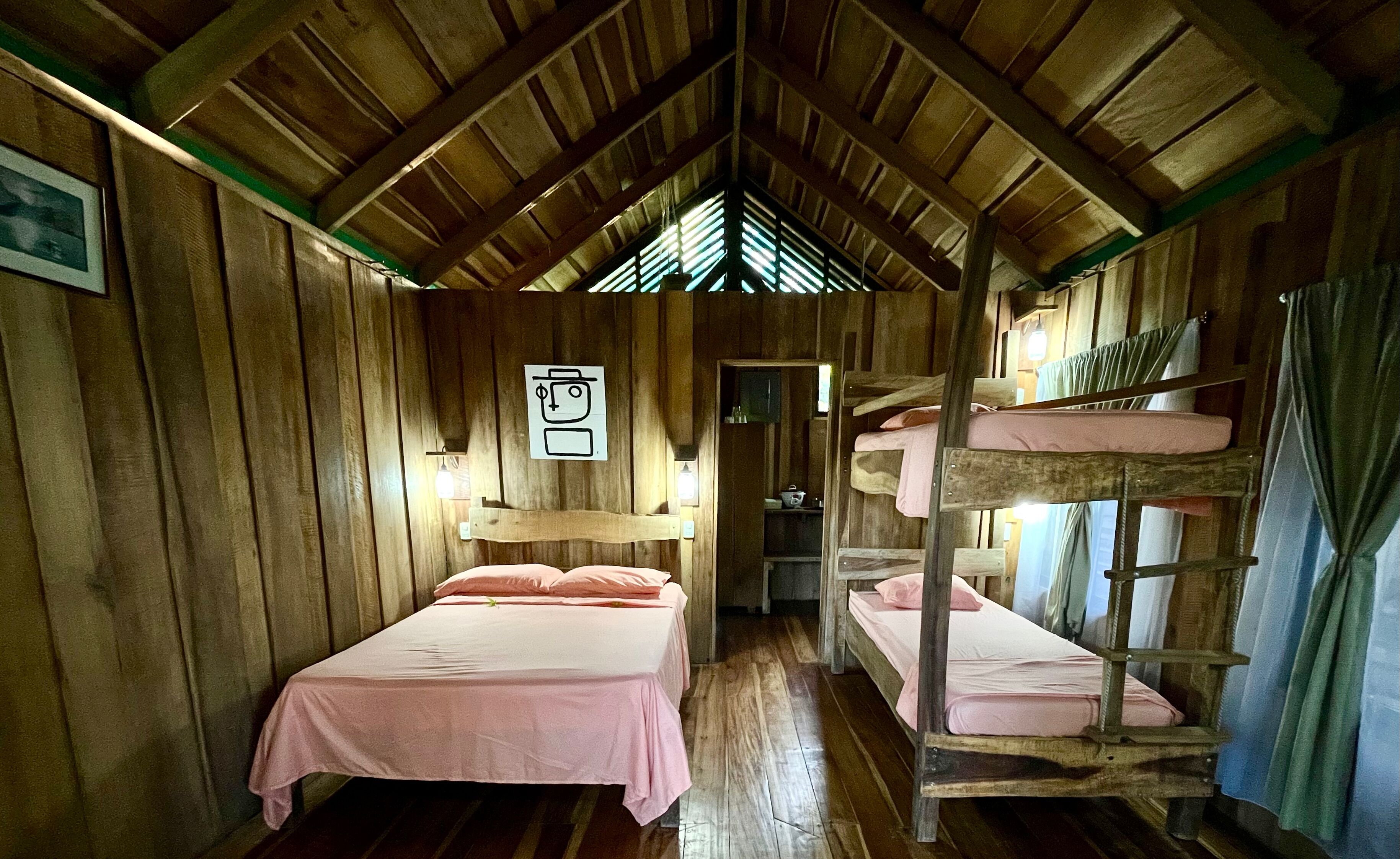 A wooden cabin with bunk beds, a small kitchenette, and a framed picture on the wall.
