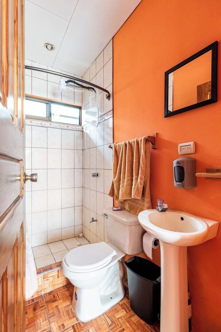 A bathroom with a shower, toilet, sink, and a towel rack.