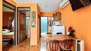 A compact living space with a dining area, a kitchenette, and a bed.
