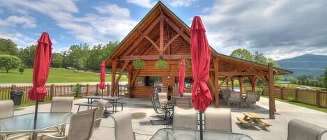 Un pavillon en bois doté d’un espace extérieur avec des tables, des chaises et des parasols rouges.