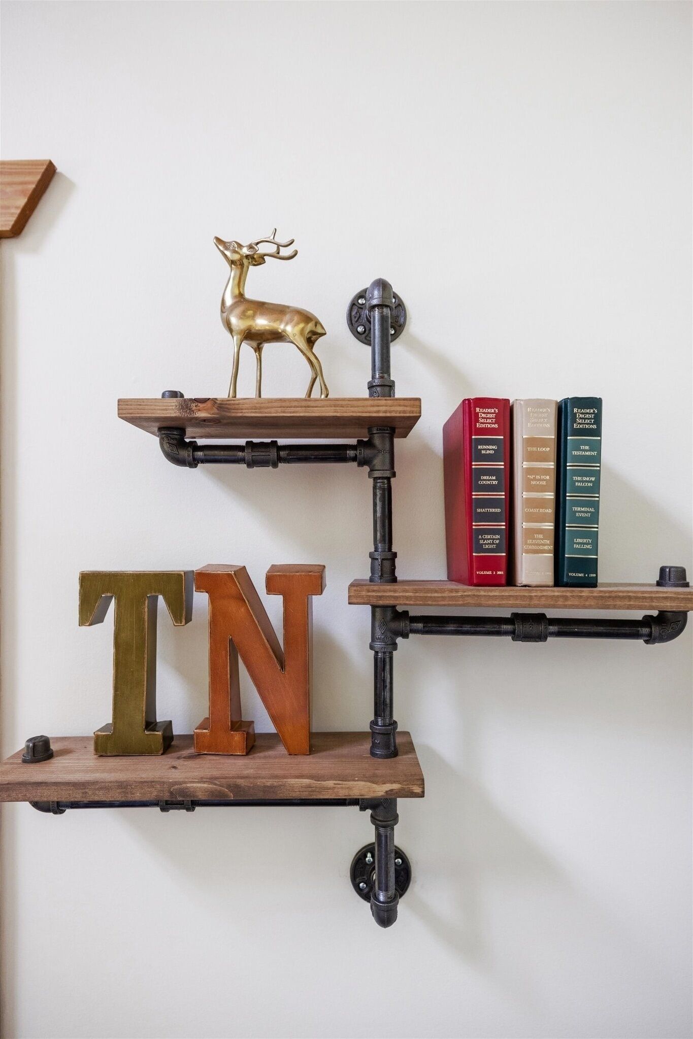 A wall-mounted shelf unit with three levels, each holding different items.