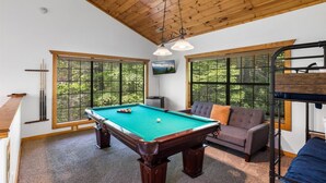 A pool table in a room with large windows, a sofa, and a bunk bed. - Whitetail Cabin 2 Bedroom Cabin by RedAwning (Gatlinburg)