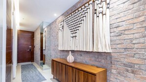 A hallway with a wooden console table, a patterned wall, and a door. - Perfect, freshly decorated one bedroom Loft 268! (Puerto Vallarta)