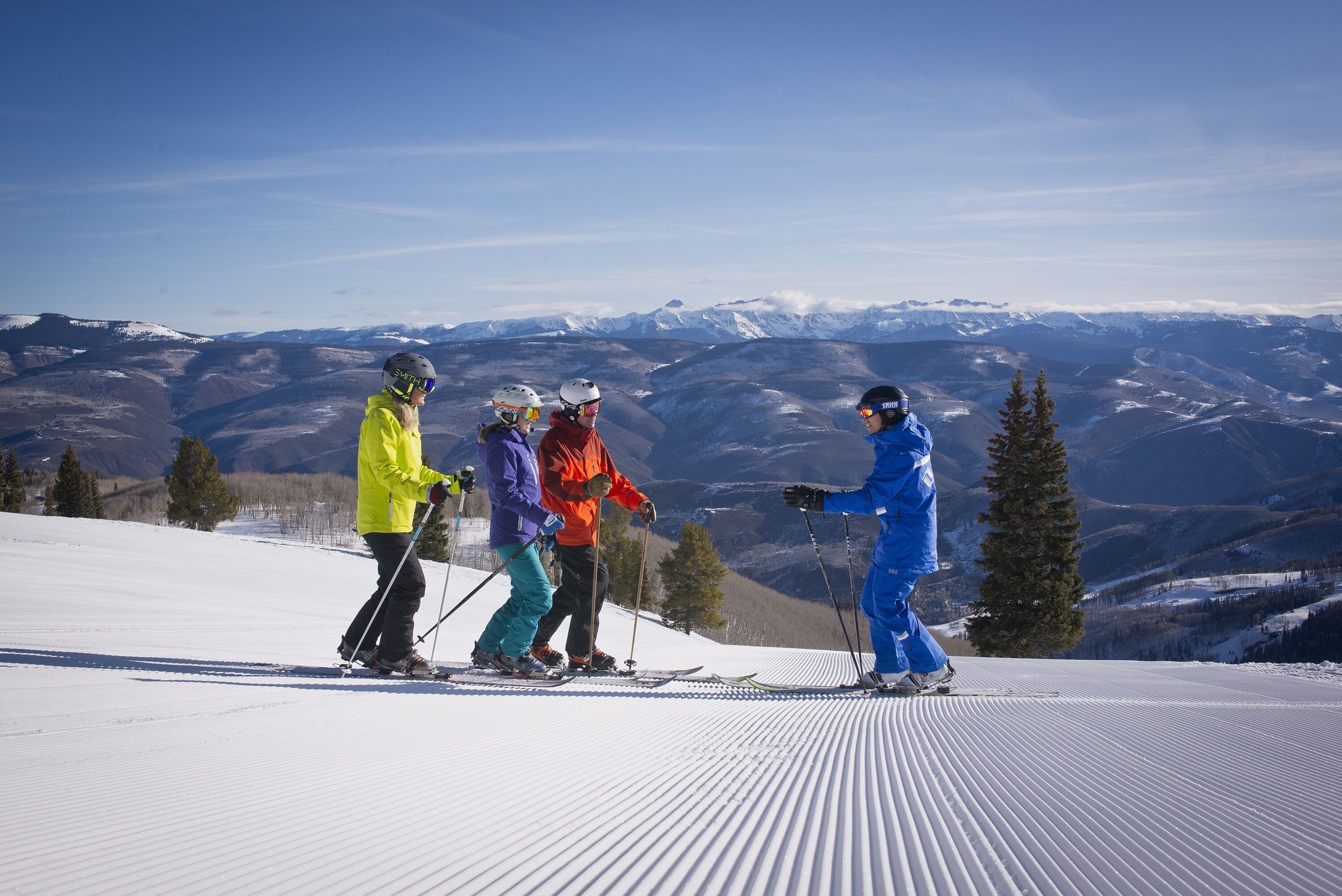 A group of skiers on a snowy slope with a mountainous backdrop.