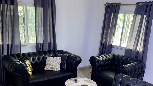 Ein Wohnzimmer mit zwei schwarzen Ledersofas, einem runden Couchtisch und einem kleinen Beistelltisch.