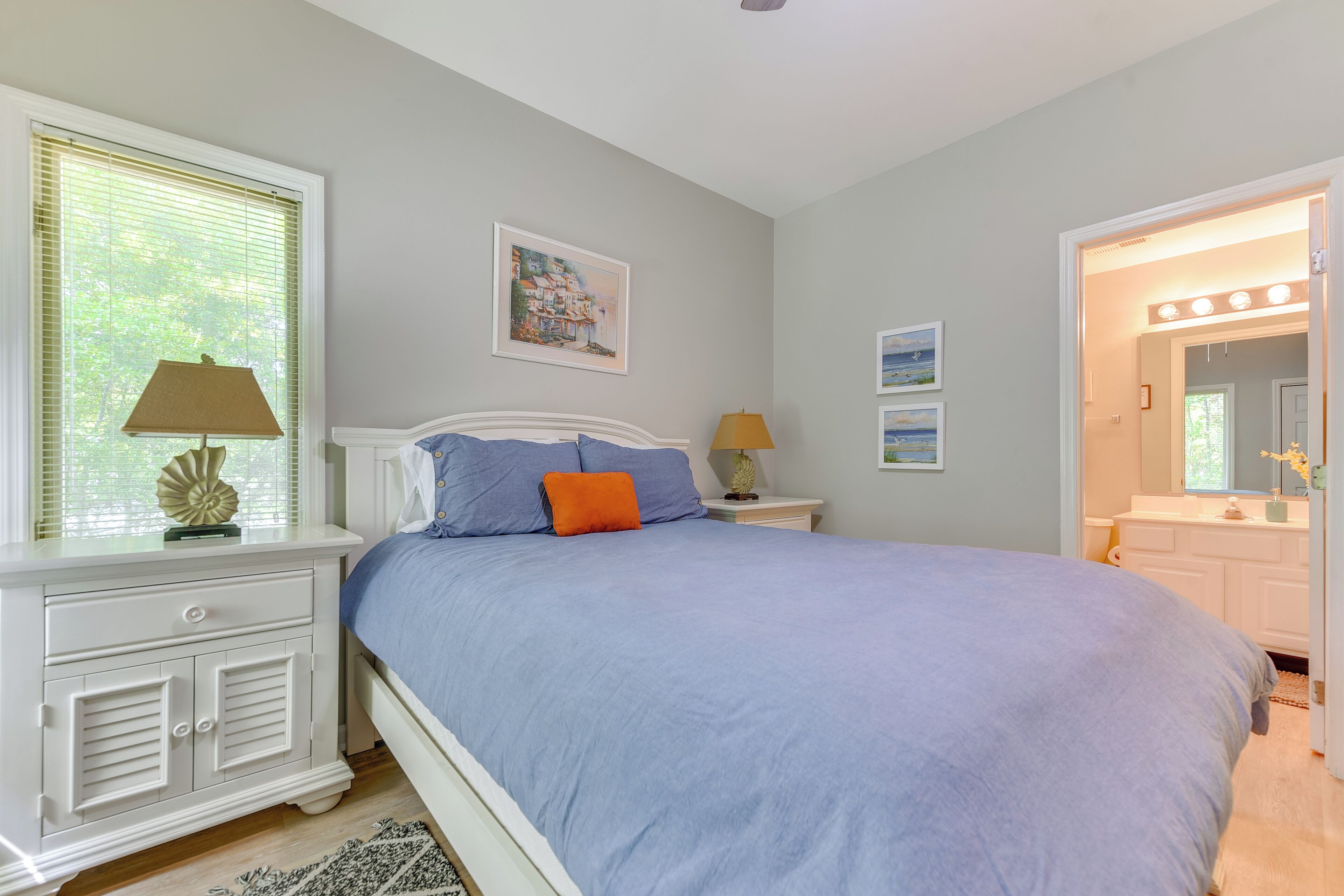A bedroom with a bed, nightstands, a dresser, and a walk-in closet.