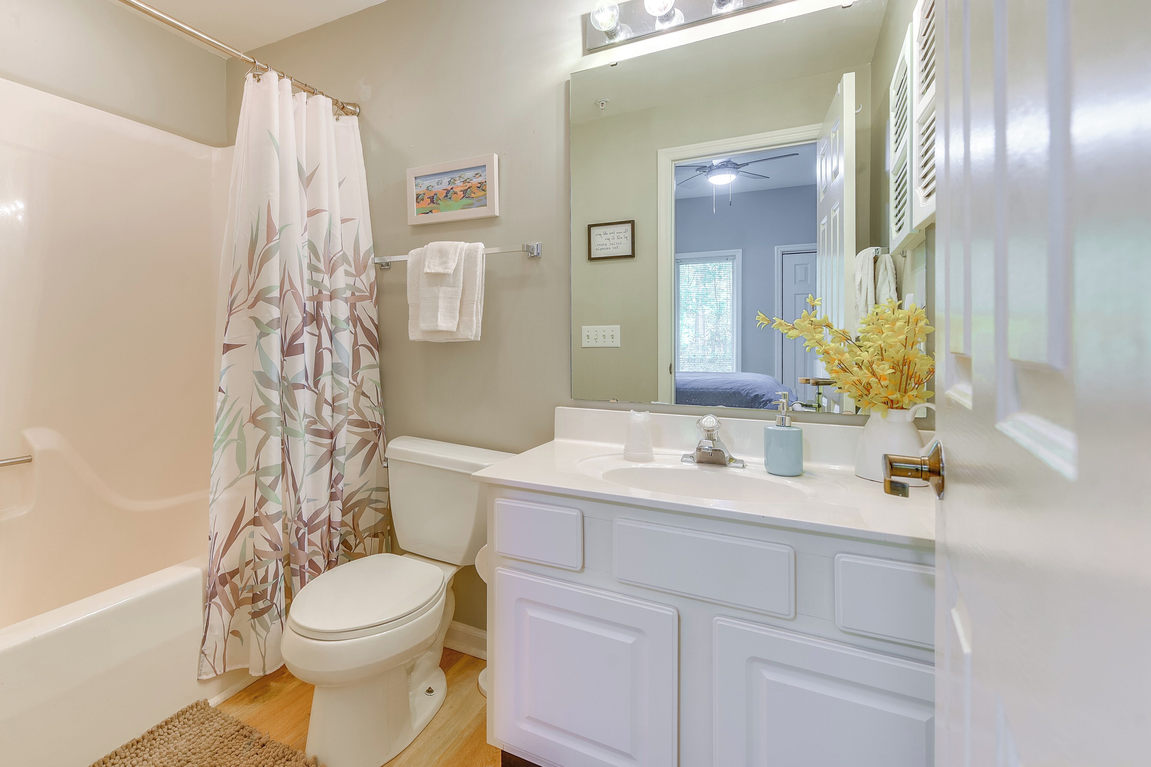 A bathroom with a bathtub, toilet, and vanity with a mirror.