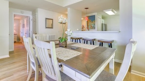 A dining area with a wooden table, white chairs, and a vase of white flowers.