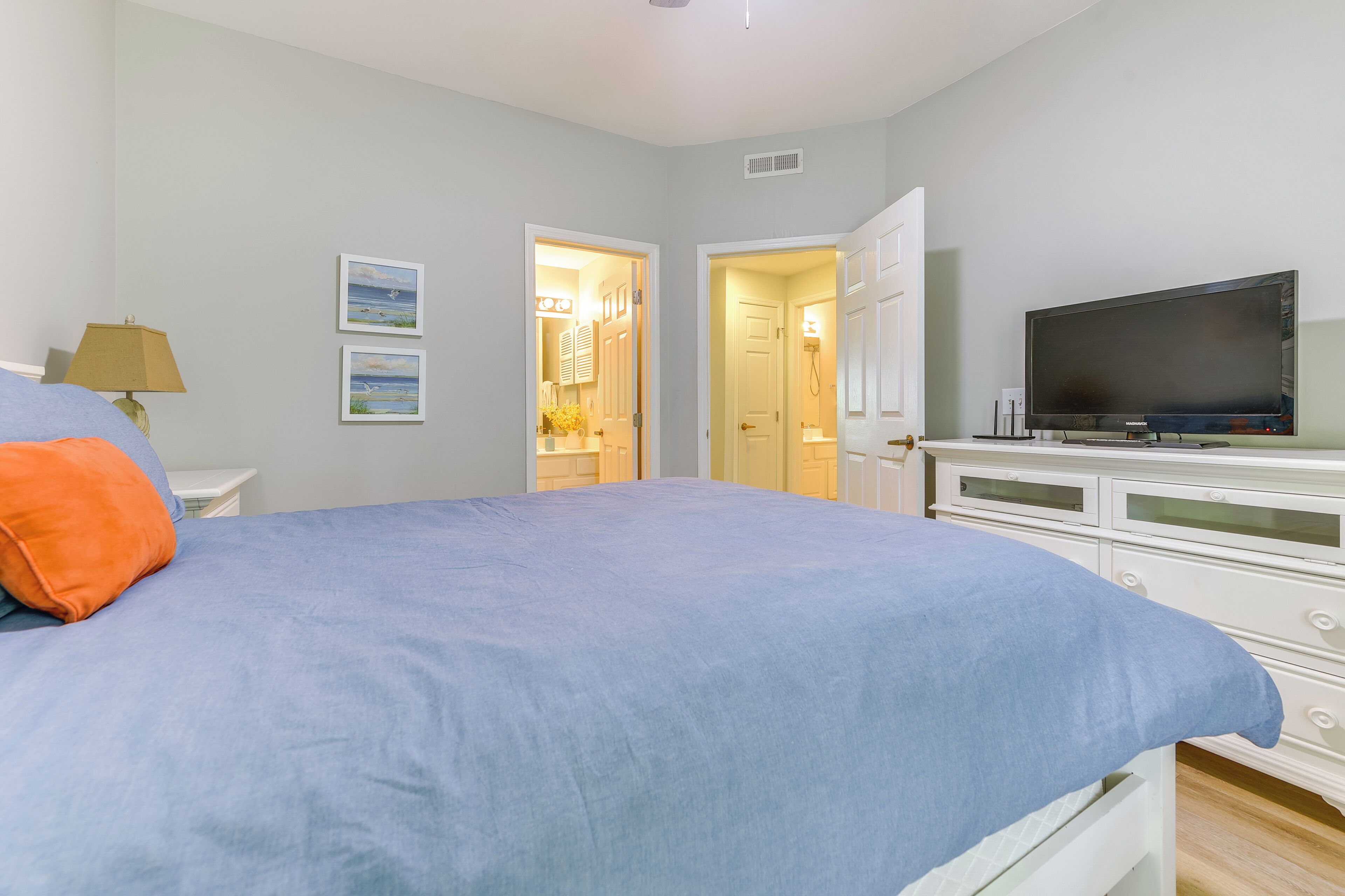 Un dormitorio con una cama, televisión y cómoda.