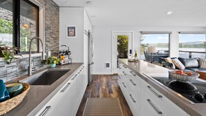 Una cocina moderna con una isla grande, electrodomésticos de acero inoxidable y vistas al exterior.