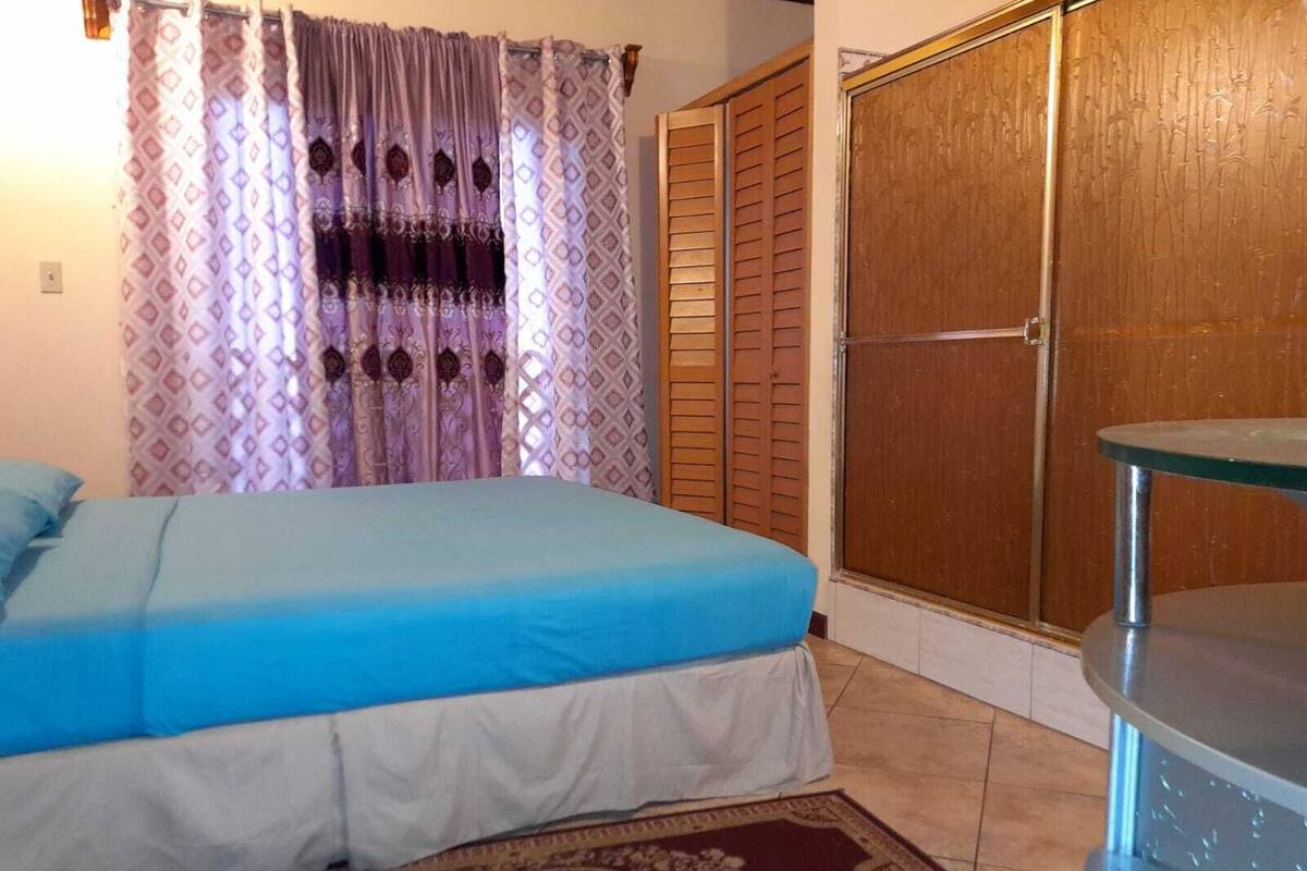 A bedroom with a bed, a wooden wardrobe, and a small table.