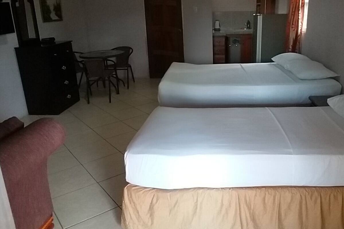 A hotel room with two beds, a desk, and a chair.