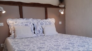 A bed with a floral-patterned bedspread, a wooden headboard, and two wall-mounted lights. - La ferme de Manon les Lavandes in an 18th century farmhouse (MONTFERRAT)