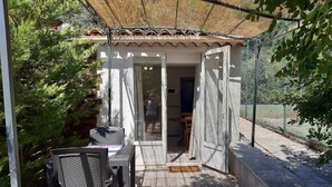 An outdoor patio with a table and chairs, a covered seating area, and a view of a house in the background. - La ferme de Manon les Lavandes in an 18th century farmhouse (MONTFERRAT)